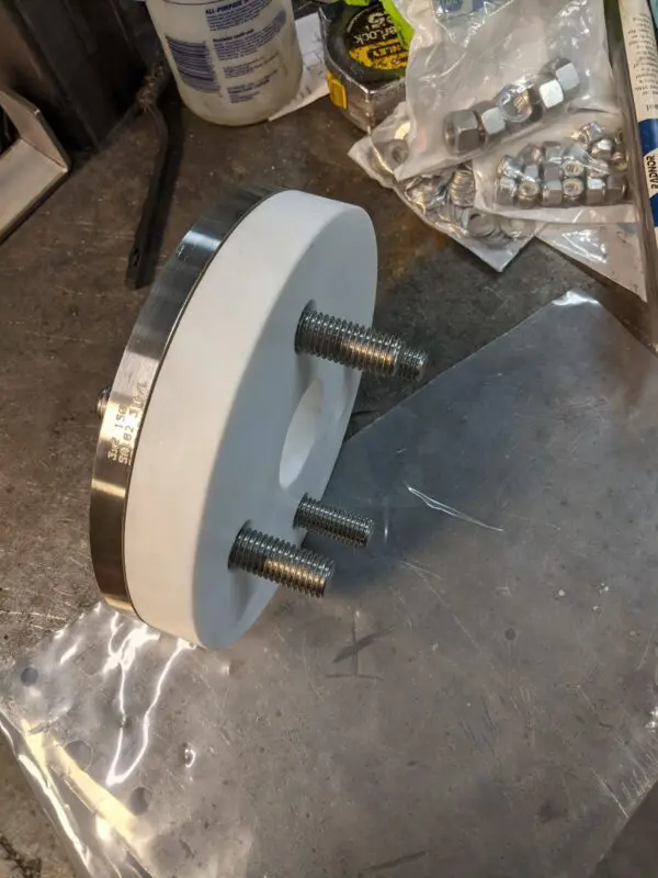A white metal wheel with four nuts on it.
