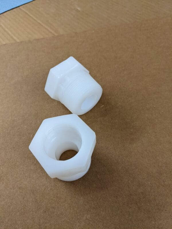 A white plastic nut and a small white piece of plastic.