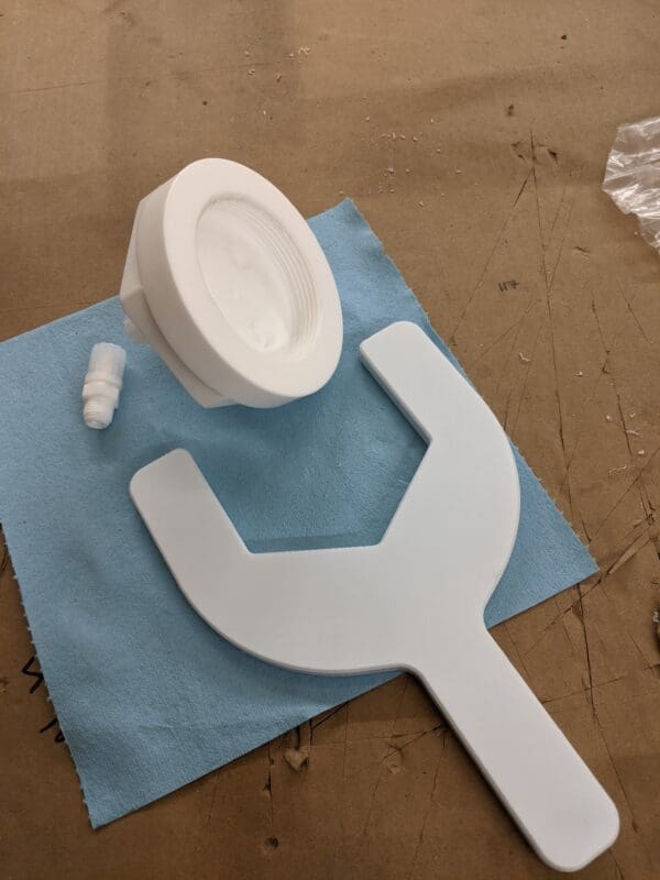 A white plastic wrench and toilet paper on top of blue paper.