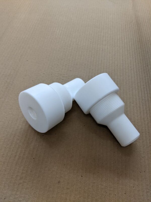A pair of white plastic plugs on top of cardboard.
