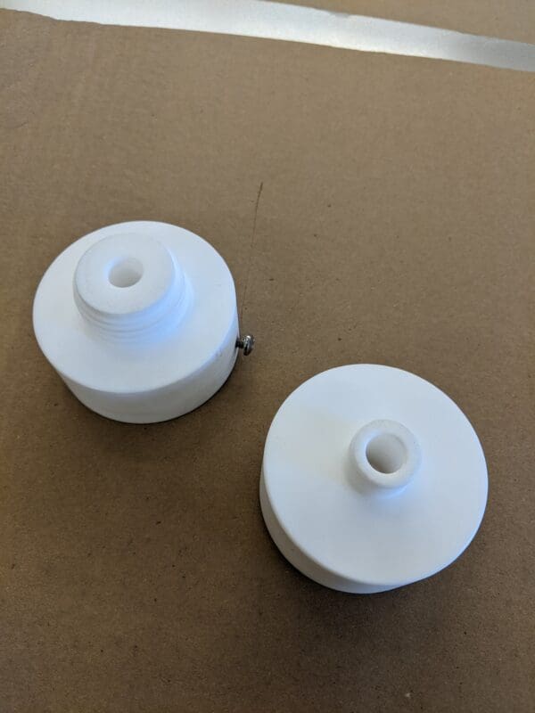 Two white spools of thread sitting on top of a table.