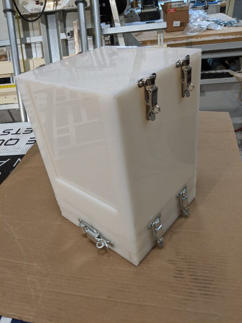 A white box with metal handles on top of cardboard.