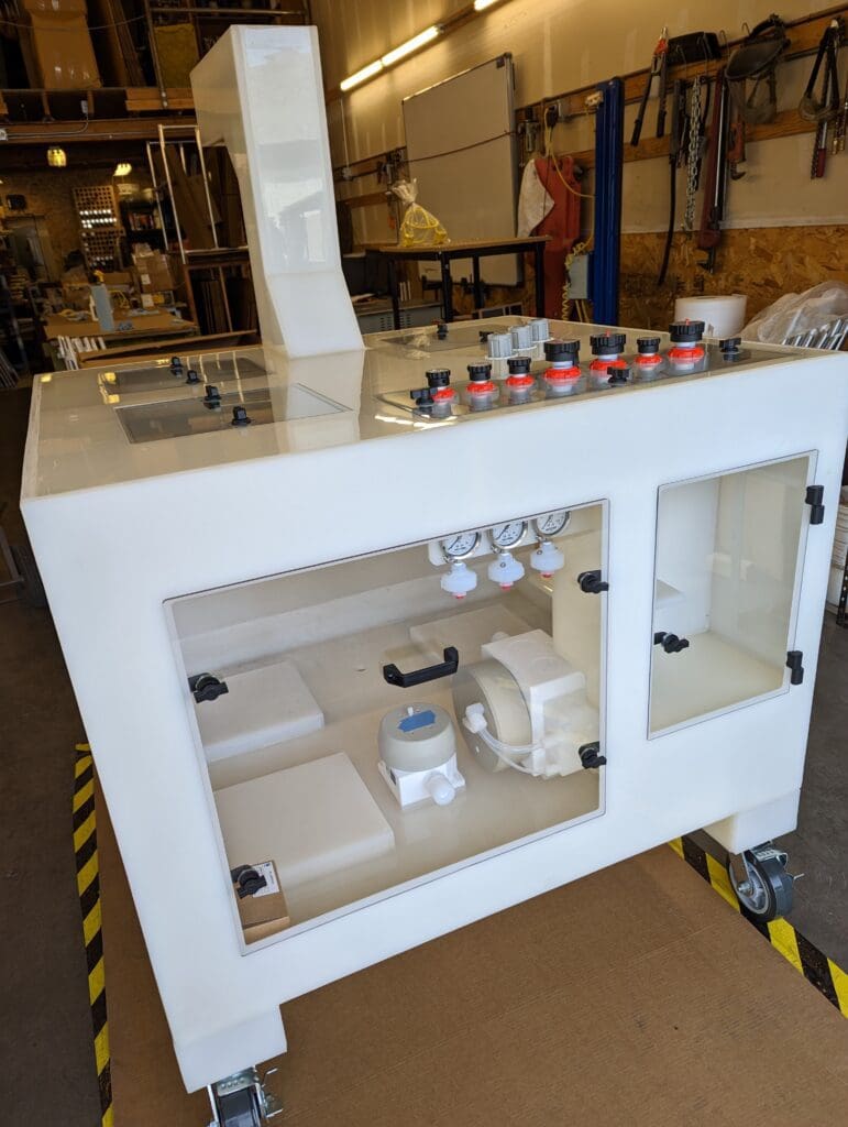 A mobile white workstation with drawers and shelves, equipped with various tools and materials, located in a workshop setting.