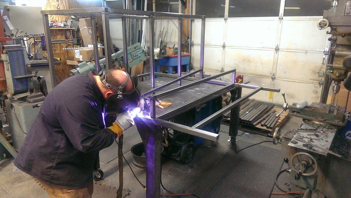 A man welding metal in an industrial setting.